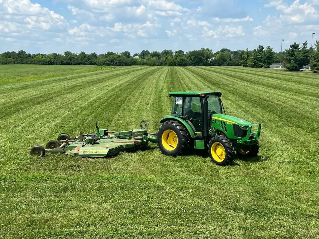 Tractor with a batwing mower on a freshly mowed field