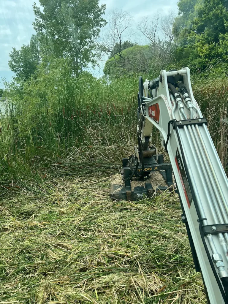 Boom mower cutting overgrowth on a ditch slope