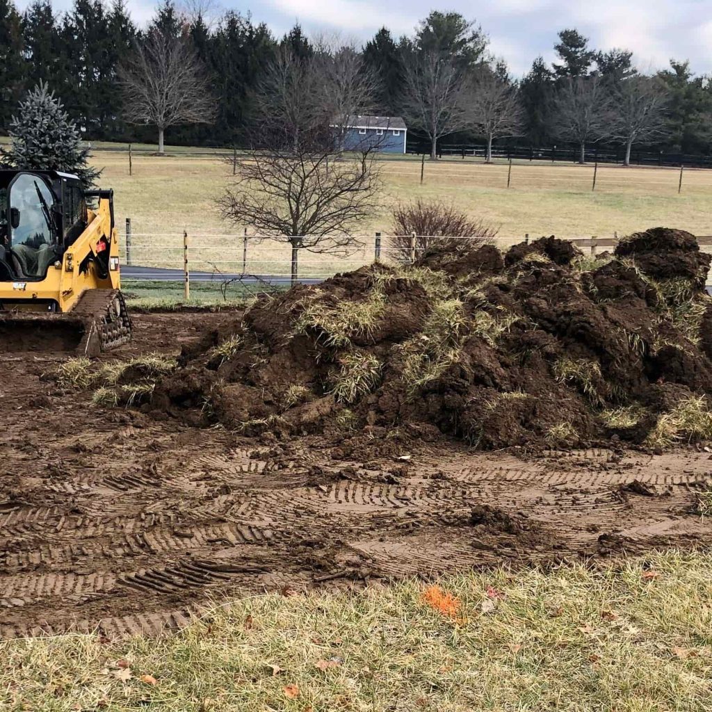 Topsoil pile and skid steer on a grading project