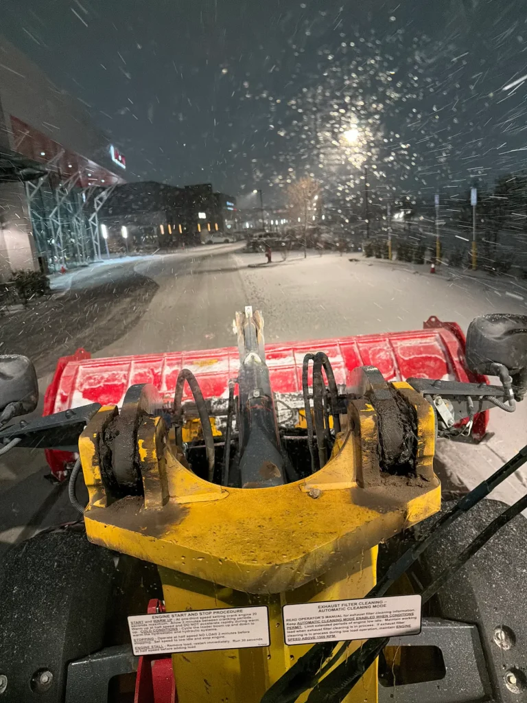 Clearing snow from a large parking lot at night
