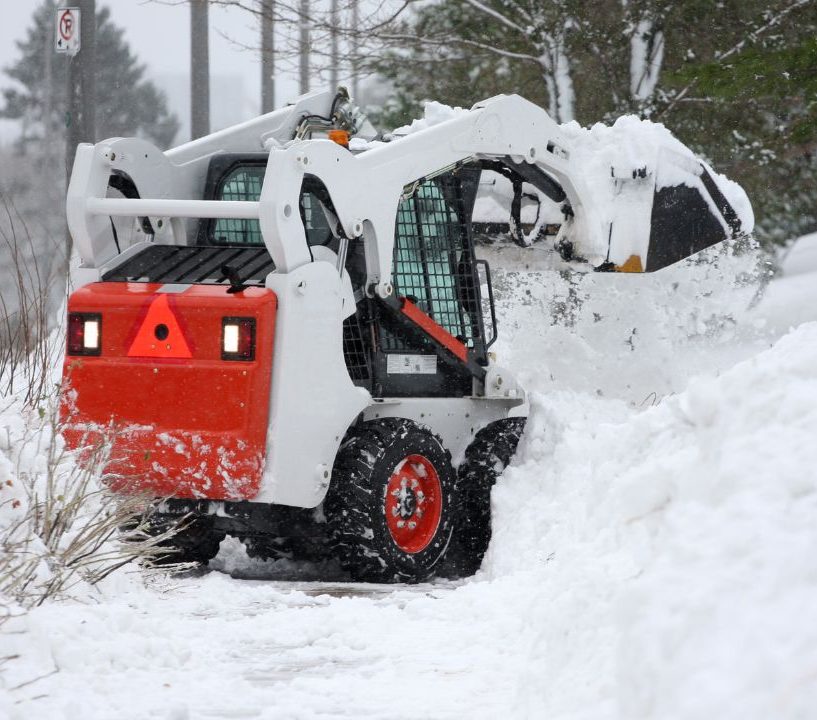 Skid steer pushing deep snow on a residential property